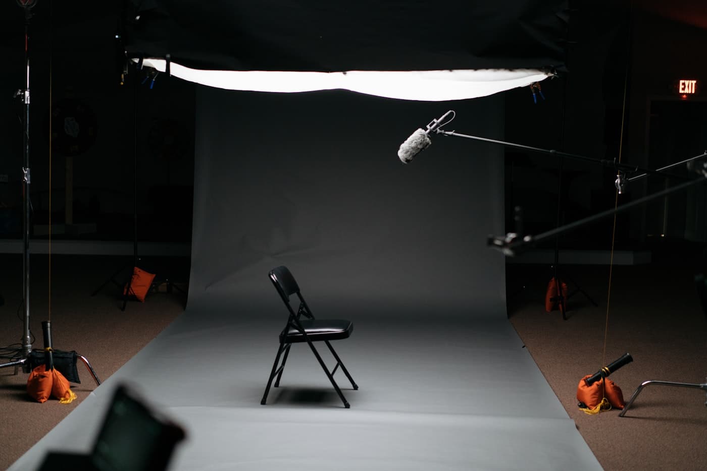 Interview-Setup im Studio: Stuhl vor grauem Hintergrund, Richtmikrofon und Softbox bereit für den Dreh