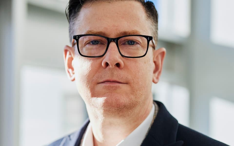 Managing Partner von Nordlicht Advisory im dunkelblauen Anzug vor hellem Bürofenster
